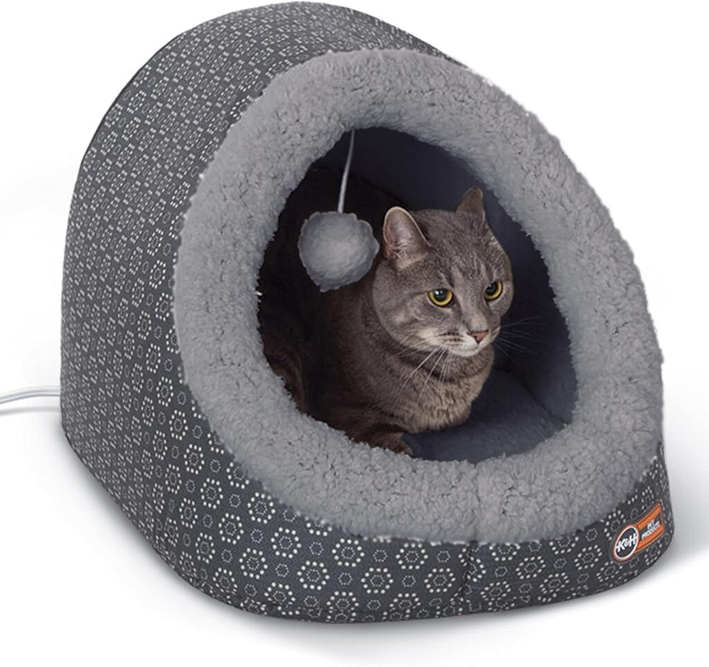 Senior calico cat resting inside a heated indoor cat house for arthritis relief.